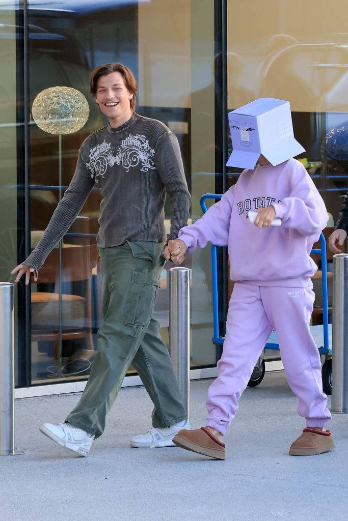 Jake Bongiovi i Millie Bobby Brown spacerują razem w 2023 roku, Millie w nietypowym pudełku na głowie.