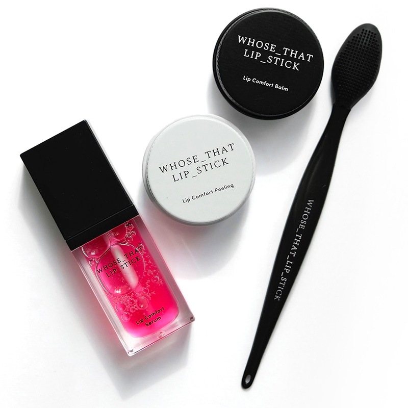 Na zdjęciu znajdują się kosmetyki do ust: różowy serum, peeling oraz balsam "Whose That Lip Stick", obok szczoteczka do ust.