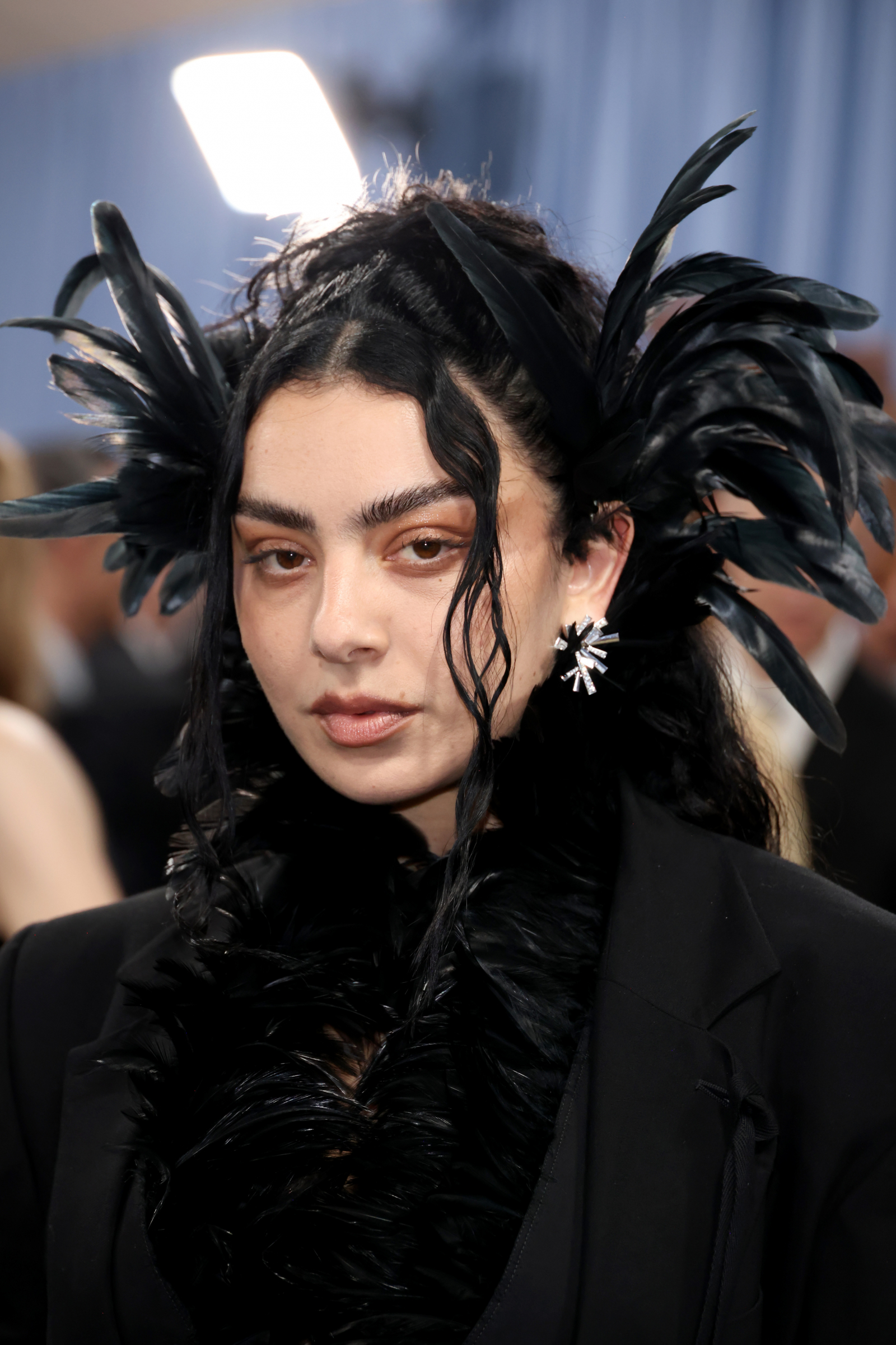 Charli XCX w stylizacji gothic glamour na Met Gala 2025, z wyrazistymi piórami i eleganckim makijażem.