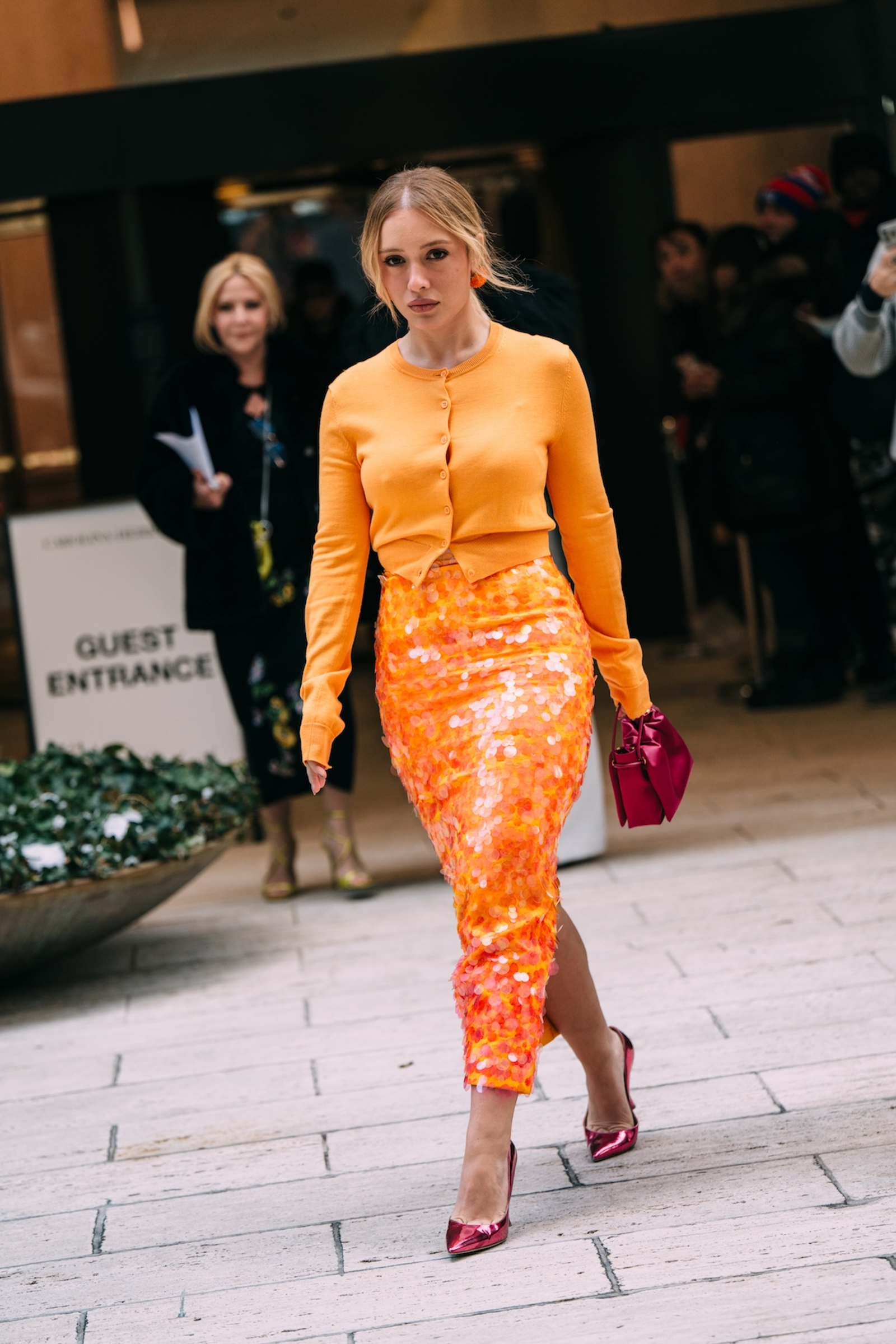 Stylizacja z cekinową spódnicą midi w kolorze pomarańczowym z kolekcji Carolina Herrera oraz pomarańczowym sweterkiem.