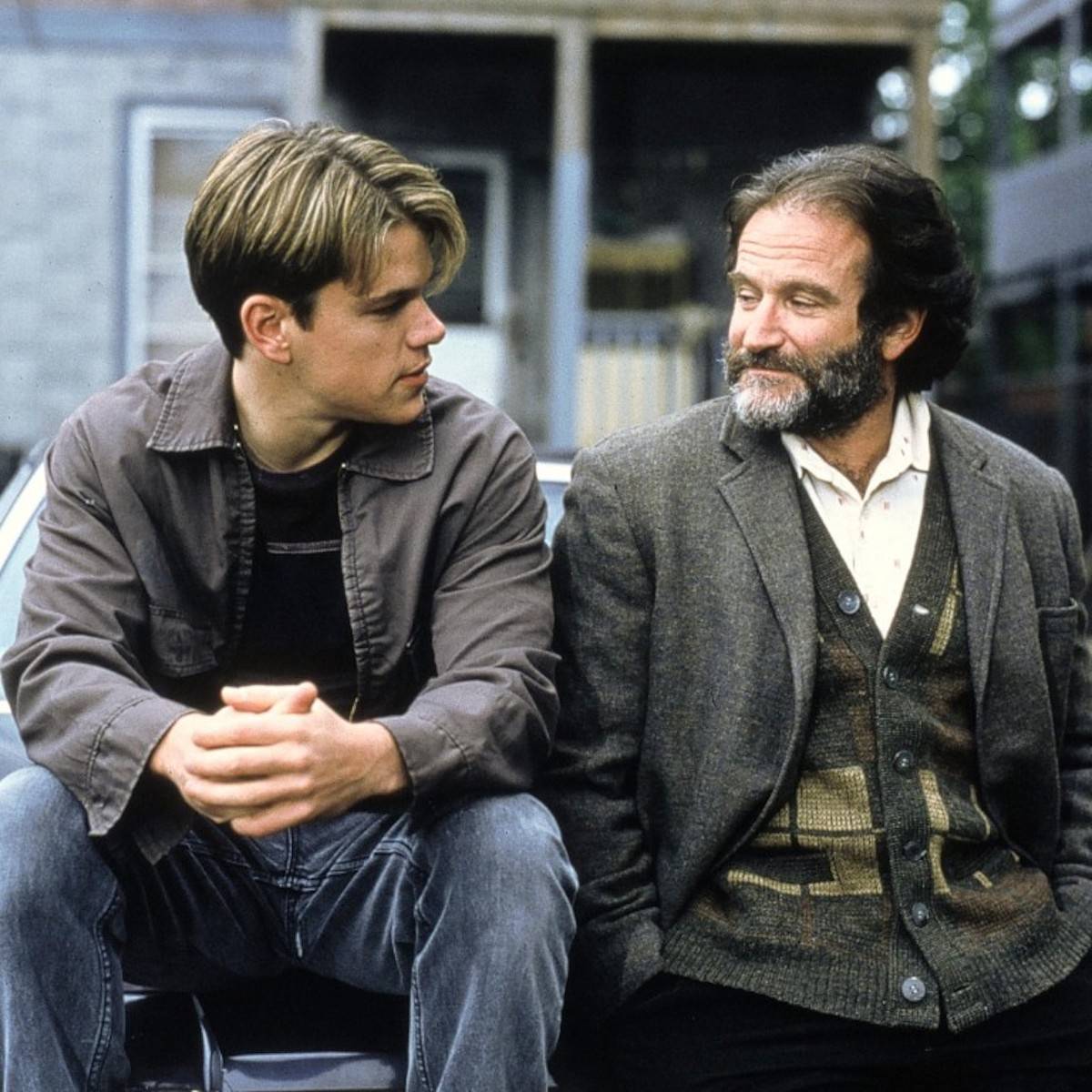 Matt Damon i Robin Williams w filmie „Buntownik z wyboru” rozmawiają na ławce, ukazując emocjonalną więź.