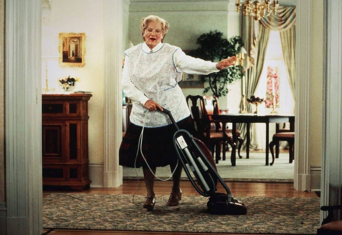 Robin Williams w filmie „Pani Doubtfire” przebiera się za kobietę i korzysta z odkurzacza w eleganckim wnętrzu.