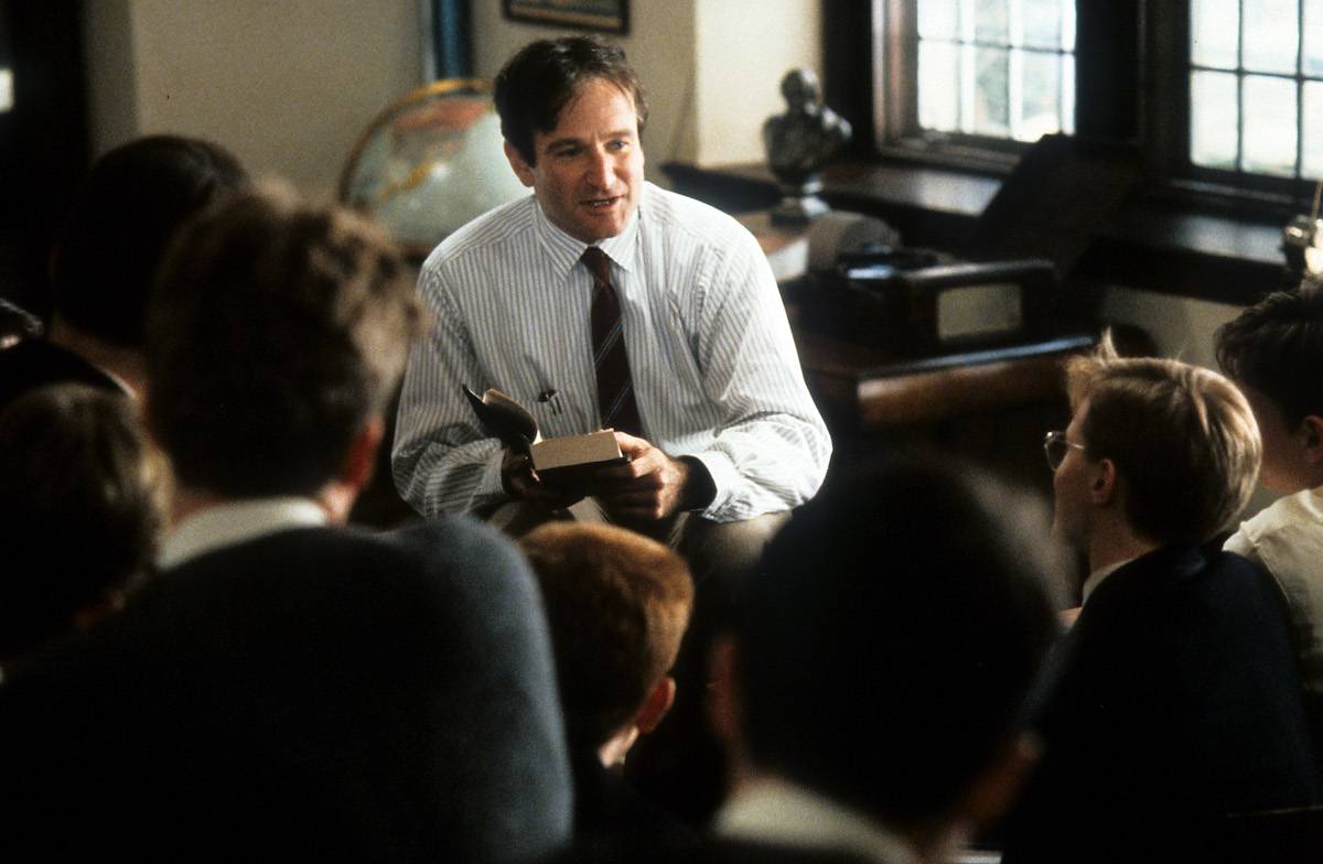 Robin Williams w filmie „Stowarzyszenie Umarłych Poetów” prowadzi lekcję w klasie, otoczony przez uczniów.