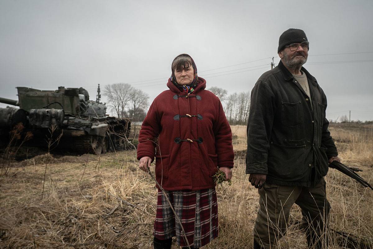 Maria z mężem obok domu i zniszczonego rosyjskiego czołgu. Podczas okupacji 15 rosyjskich żołnierzy weszło do ich domu, gdzie żyli przez 3 dni. 31.03.2022 region Czernihowa (fot. Patryk Jaracz)